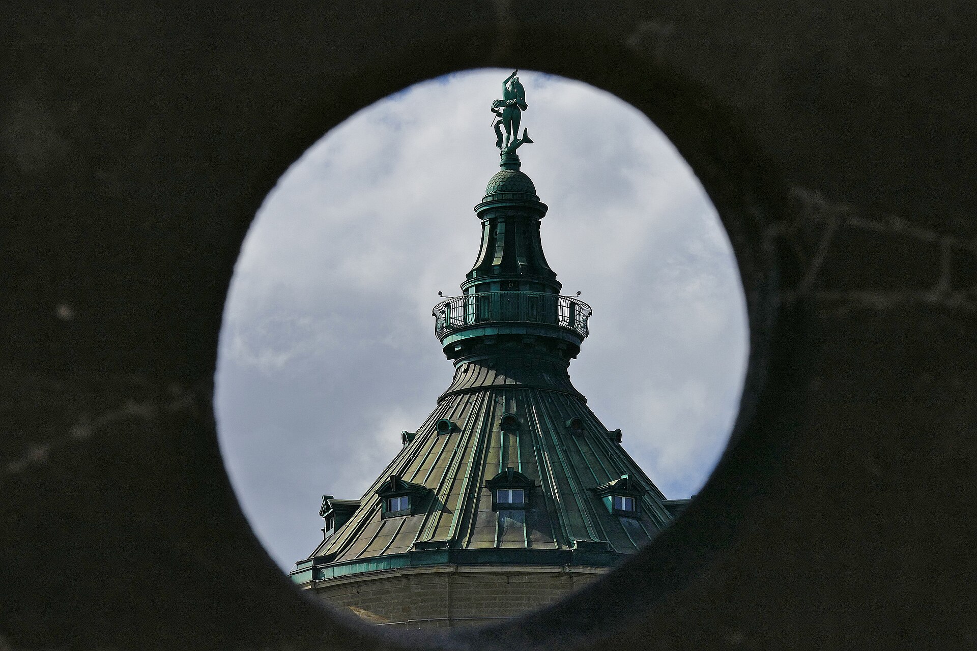 Durchblick auf die Spitze des Mannheimer Wasserturms durch eine kreisrunde Öffnung — Bronze-Figur und Kupferdach